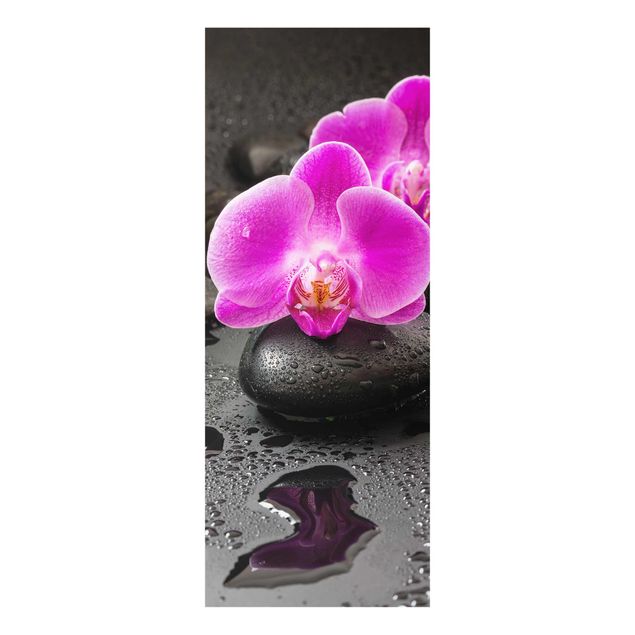 Glasbild - Pinke Orchideenblüten auf Steinen mit Tropfen - Hochformat